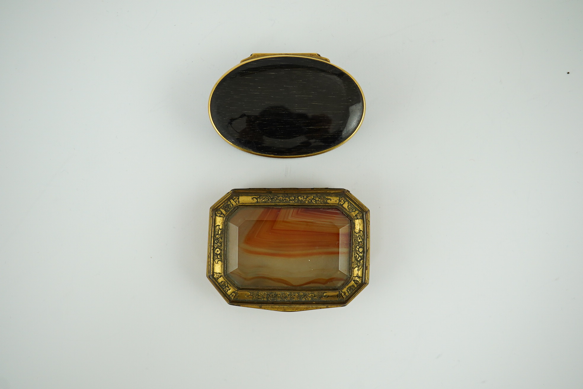 An early 19th century German gold mounted rutile agate? oval snuff box, 64mm and another gilt copper mounted agate snuff box.